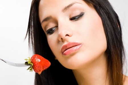 Beautiful young brunette with ripe strawberry dripping honey.の写真素材