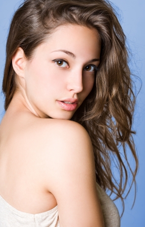 Portrait of a beautiful young brunette woman on blue background.の写真素材