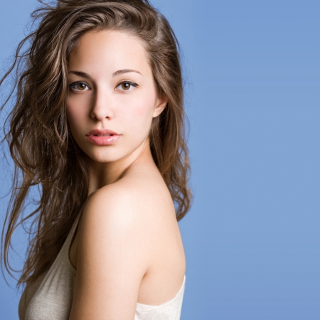 Portrait of a beautiful young brunette woman on blue background.の写真素材