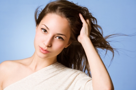 Portrait of a brunette beauty coming through her wind swept hair with hands.の写真素材