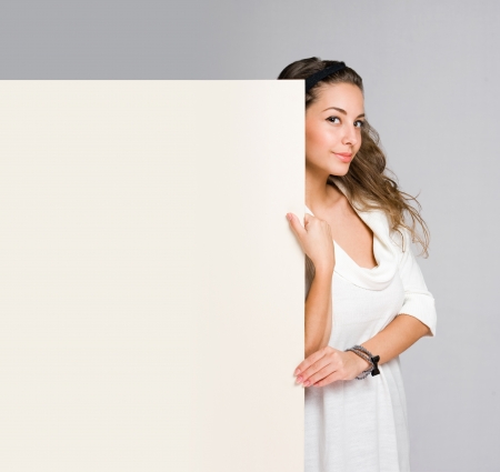 Happy beautiful young woman with empty billboard の写真素材