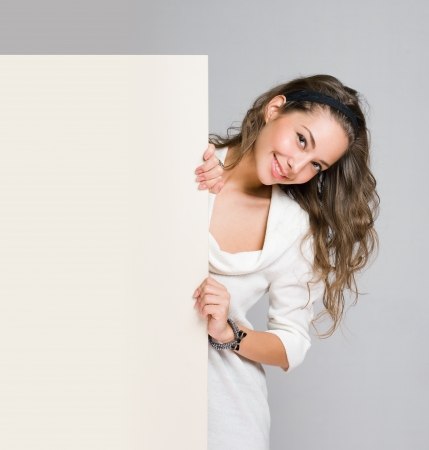 Gorgeous young brunette woman holding blank white billboard の写真素材