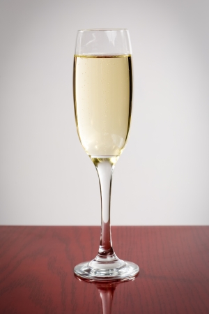 Closeup shot of elegant champagne glass on dark reflective wood.の写真素材