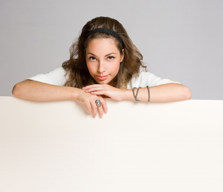 Beautiful young brunette woman holding large white banner for copy space.の写真素材