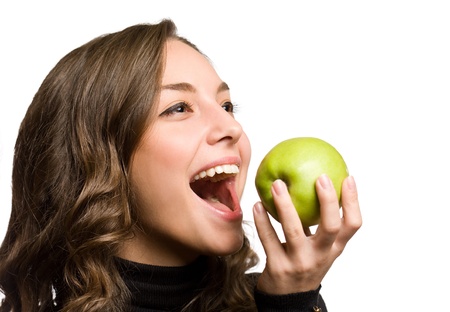 Gorgeous young brunette with healthy teeth biting into green apple.の写真素材