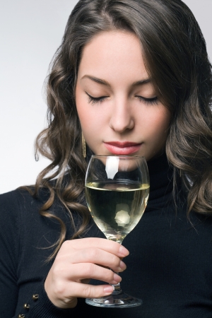 Portrait of a beautiful young brunette woman tasting, checking white wine.の写真素材
