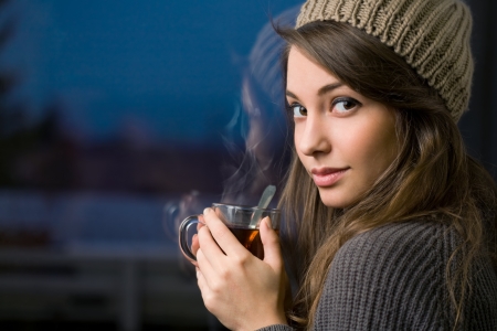 Gorgeous young brunette woman holding mug of hot tea.の写真素材