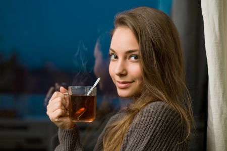 Attractive young brunette woman with mug of hot tea.の写真素材