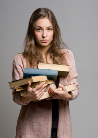 Stressed looking young student woman with lots of books.の写真素材