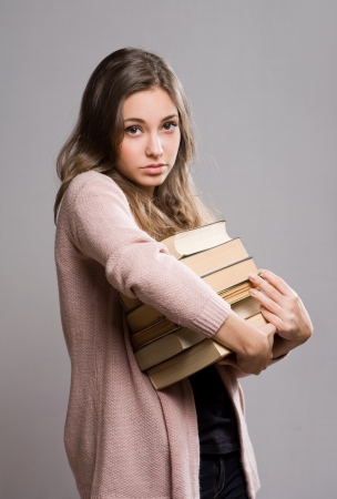 Portrait of worried looking young brunette with large pile of books.の写真素材
