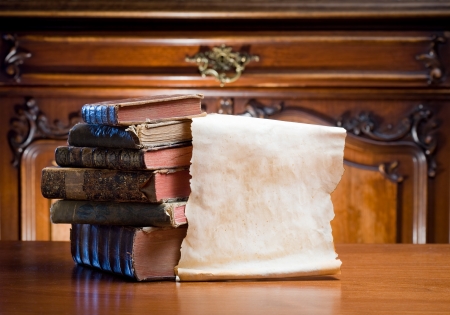 Old worn paper scroll with copy space next to antique books.の写真素材
