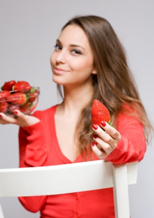 Fit young brunette woman with a bowl of juicy fresh strawberriesの写真素材