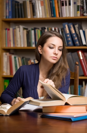 Portrait of young student studying among lot of books.の写真素材