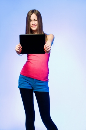 Colorful dressed expressive teen beauty holding tablet computer for copy space の写真素材