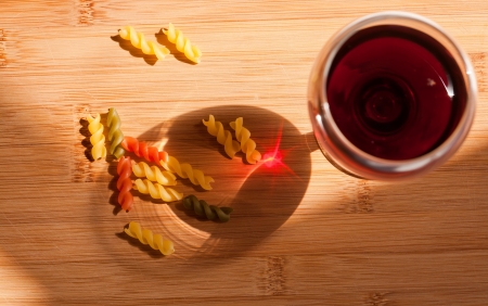 Still life with colorful pasta and glass of red wine and colorful bottle in natural lighting の写真素材