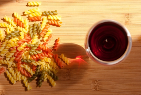 Still life with colorful pasta and glass of red wine and colorful bottle in natural lighting の写真素材