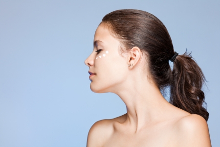 Portrait of a beautiful young brunette using lotion.の写真素材