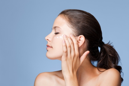 Portrait of a young brunette beauty using lotion.の写真素材