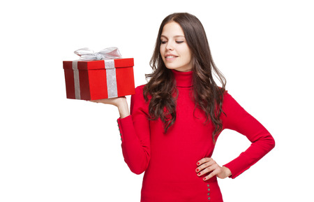 Portrait of a brunette christmas beauty holding shiny red gift box.の写真素材
