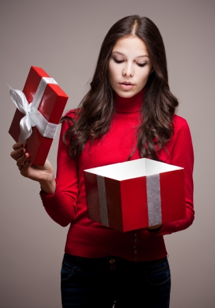 Portrait of a beautiful young brunette woman holding gift box with mysterious light.の写真素材