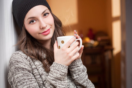 Portrait of a gorgeous young bruette woman relaxing with mug of hot beverage.の写真素材