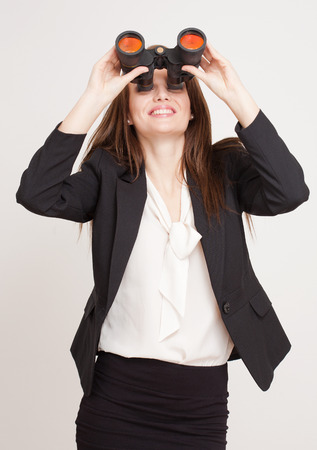 Portrait of a gorgeous young businesswoman using binoculars.の写真素材