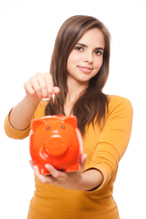 Portrait of a beautiful young brunette posing with colorful piggy bank.の写真素材