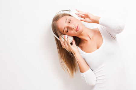 Portrait of blond beauty listening to music in white headphones.の写真素材