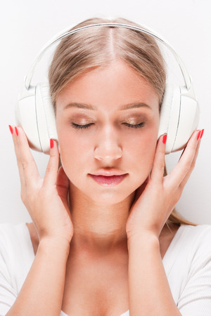 Portrait of blond beauty listening to music in white headphones.の写真素材