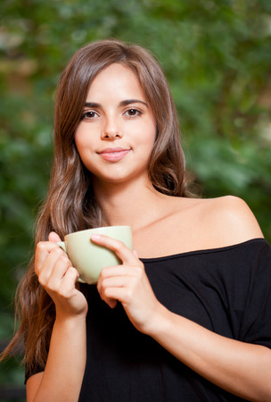 Portrait of a gorgeous cool young brunette woman holding green cup.の写真素材