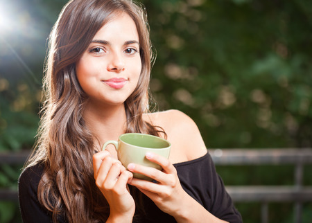 Gorgeous young brunette woman with a green cup.の写真素材