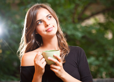Portrait of a gorgeous cool young brunette woman holding green cup.の写真素材