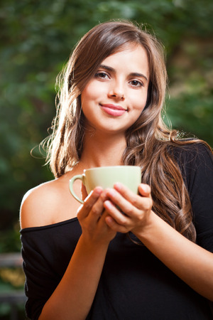 Portrait of a gorgeous cool young brunette woman holding green cup.の写真素材