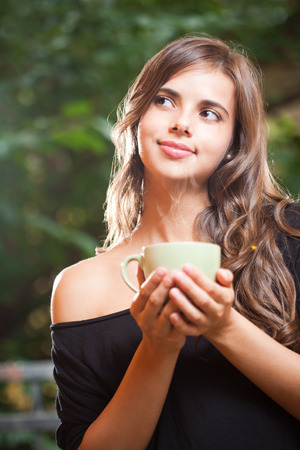 Gorgeous young brunette woman with a green cup.の写真素材