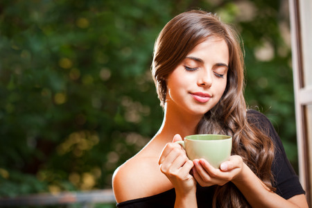 Gorgeous young brunette woman with a green cup.の写真素材