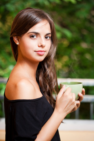 Portrait of a gorgeous cool young brunette woman holding green cup.の写真素材
