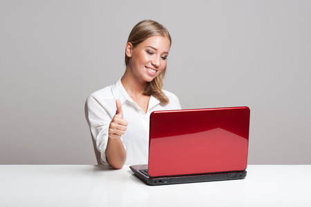 Portrait of a gorgeous young blond woman with her computer.の写真素材