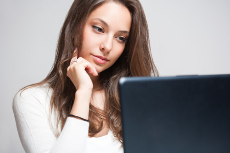 Attractive young brunette woman using her laptop.の写真素材