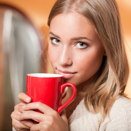 Beautiful young blond woman with mug of hot beverage.の写真素材
