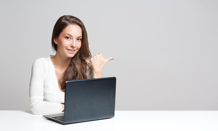 Attractive young brunette woman using her laptop.の写真素材