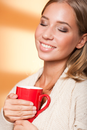 Beautiful young blond woman with mug of hot beverage.の写真素材