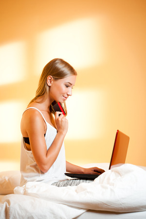 Portrait of a blond beauty using her laptop at home.の写真素材
