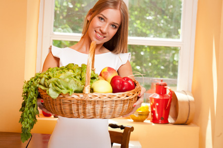 Fit gorgeous young blond woman holding wicker basket full of fresh vegetables.の写真素材