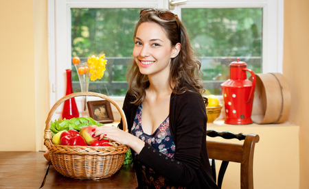 Beautiful young brunette with a basket of fresh ingredients.の写真素材