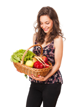Beautiful young brunette woman with a wicker basket full of vegetables and fruitsの写真素材