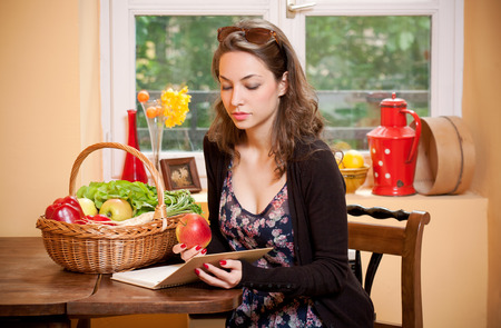 Gorgeous young brunette woman in the kitchen with basket full of healthy food.の写真素材