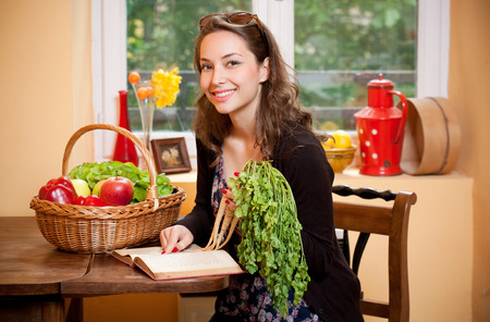 Gorgeous young brunette woman in the kitchen with basket full of healthy food.の写真素材