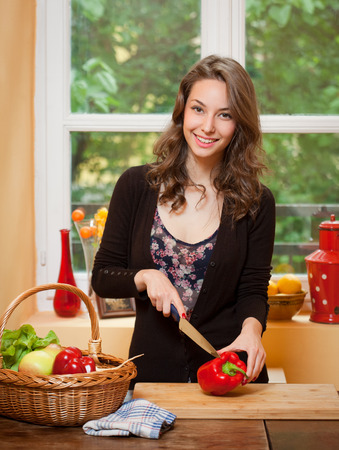 Young brunette beauty in the kitchen with large basket of vegetables and fruits.の写真素材