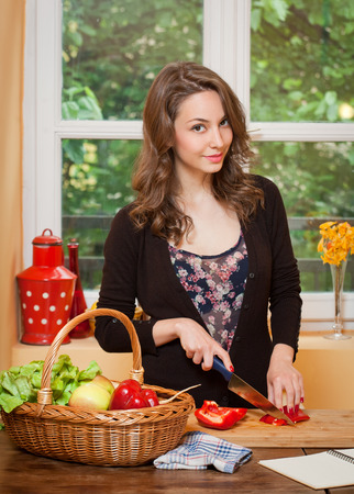 Gorgeous young brunette woman in the kitchen with basket full of healthy food.の写真素材