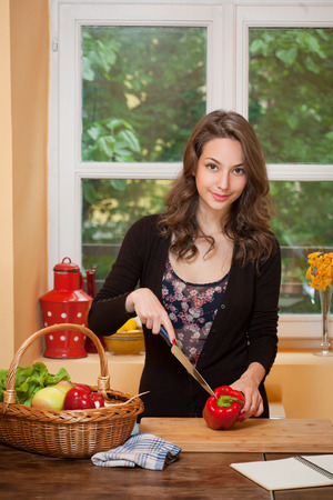 Beautiful young brunette woman preparing healthy food in the kitchen.の写真素材